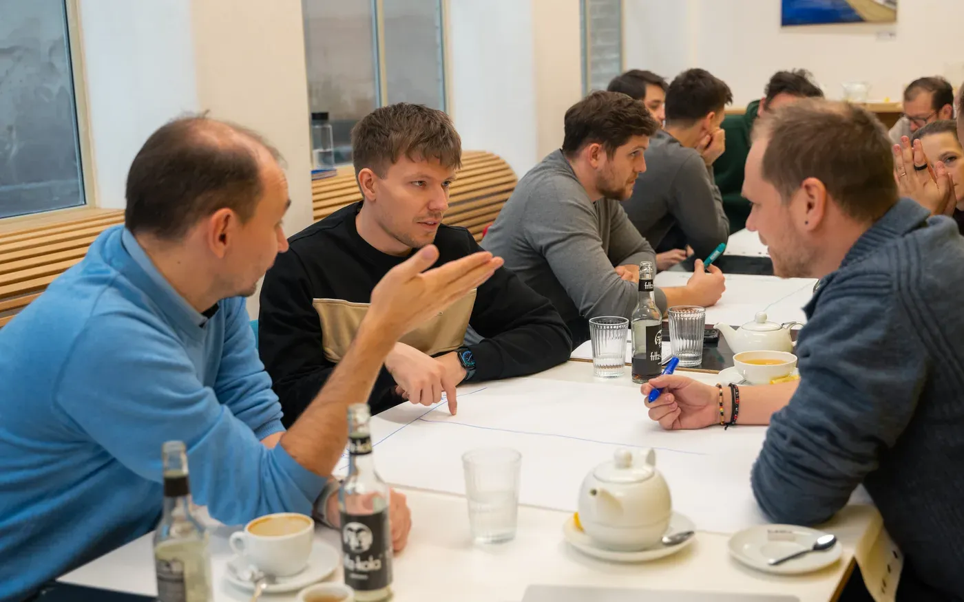 Two engineering leaders in an animated peer discussion across a workshop table