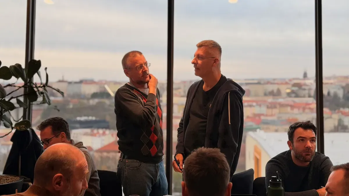 Two engineering leaders standing in discussion by the windows of a Prague training room