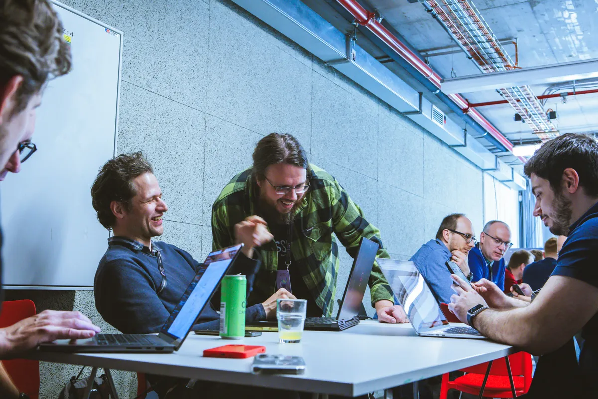 A group of engineering leaders laughing and talking around a table covered in open laptops, phones and drinks during a breakout session at the ELC Conference.