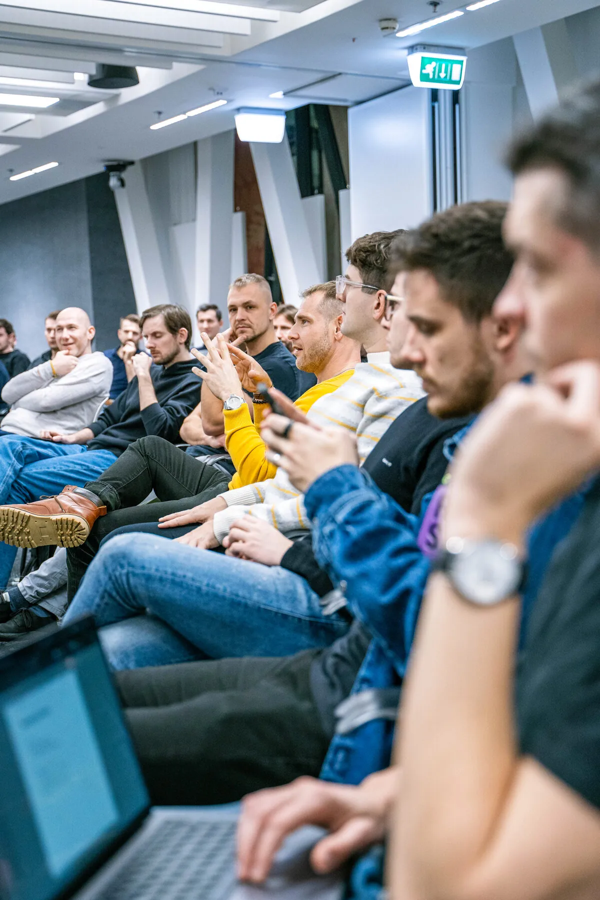 Engineering leaders seated side by side at an ELC session, laptops open, one gesturing mid conversation with the person next to him.